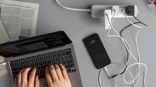Personne tapant sur un ordinateur portable, téléphone en charge